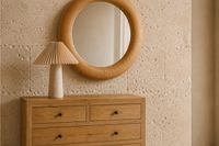 Mediterranean bedroom dresser with natural wood, sculptural table lamp and round mirror in a calm and relaxed Mallorca interior.