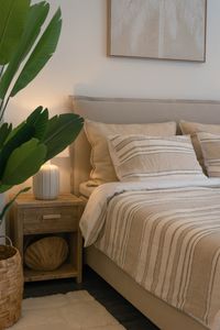 Handcrafted Swedish boxspring bed with striped bedding, upholstered headboard and soft natural textiles in a relaxed Mediterrane Handcrafted Swedish boxspring bed with striped bedding, upholstered headboard and soft natural textiles in a relaxed Mediterrane