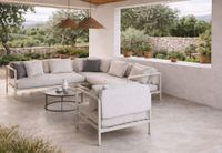 Modern Mediterranean outdoor lounge with beige sofa, armchair and coffee table on covered terrace in Mallorca Modern Mediterranean outdoor lounge with beige sofa, armchair and coffee table on covered terrace in Mallorca