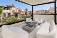 Rooftop lounge terrace in a Santa Catalina townhouse in Palma with contemporary outdoor seating, soft neutral tones and panoramic Mediterranean city views over traditional rooftops.