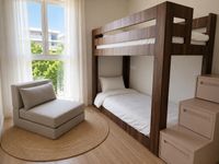 Dormitorio infantil contemporáneo en Es Molinar con litera de madera oscura, luz natural y mobiliario funcional en apartamento mediterráneo de Palma de Mallorca.