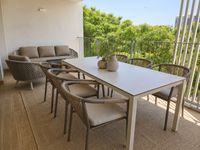 Terraza contempor&aacute;nea en Es Molinar con comedor exterior, alfombra outdoor y lounge relajado con vistas verdes en Palma de Mallorca.