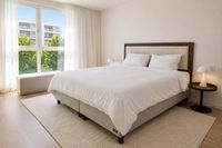 Cama continental sueca con cabecero en nogal y boucl&eacute; en dormitorio contempor&aacute;neo de Es Molinar con luz natural y estilo mediterr&aacute;neo relajado en Palma de Mallorca.